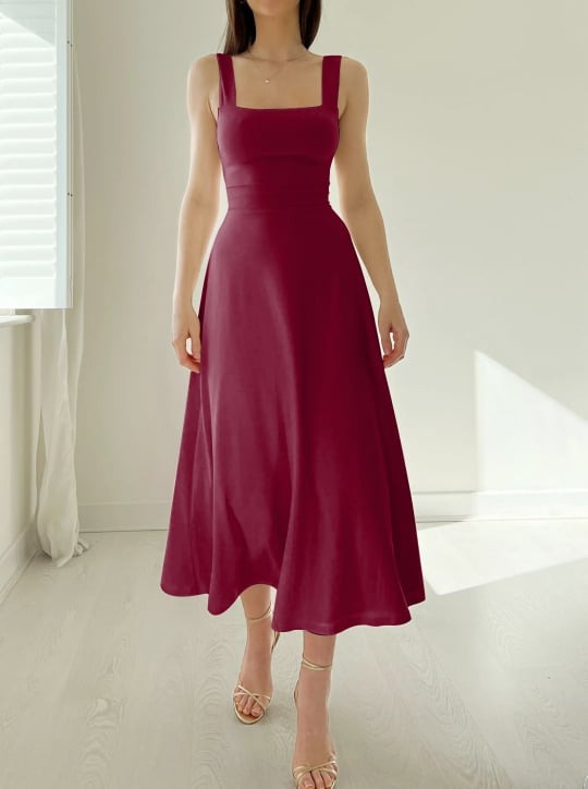 Frau trägt ein weinrotes ärmelloses Midikleid mit tailliertem Oberteil und weitem Rock.