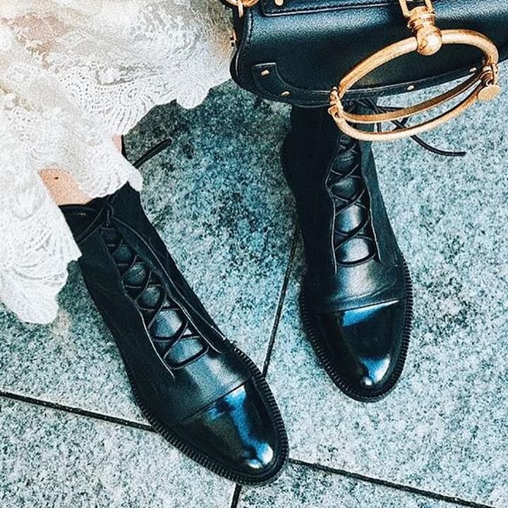 Nahaufnahme von schwarzen Vintage-Stiefeletten mit Absatz und schwarzer Tasche
