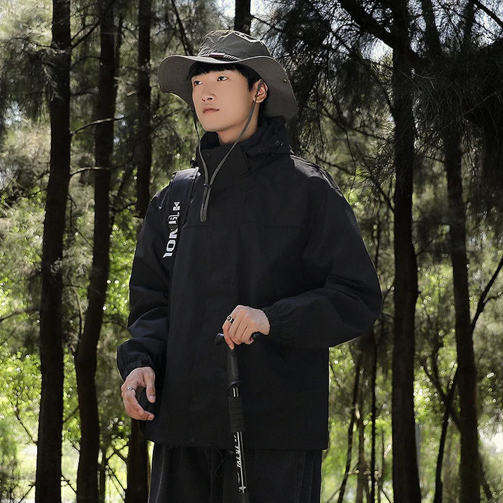 Ein Mann trägt eine wind- und wasserdichte Outdoor-Kapuzenjacke mit langen Ärmeln und farblich abgestimmtem Reißverschluss