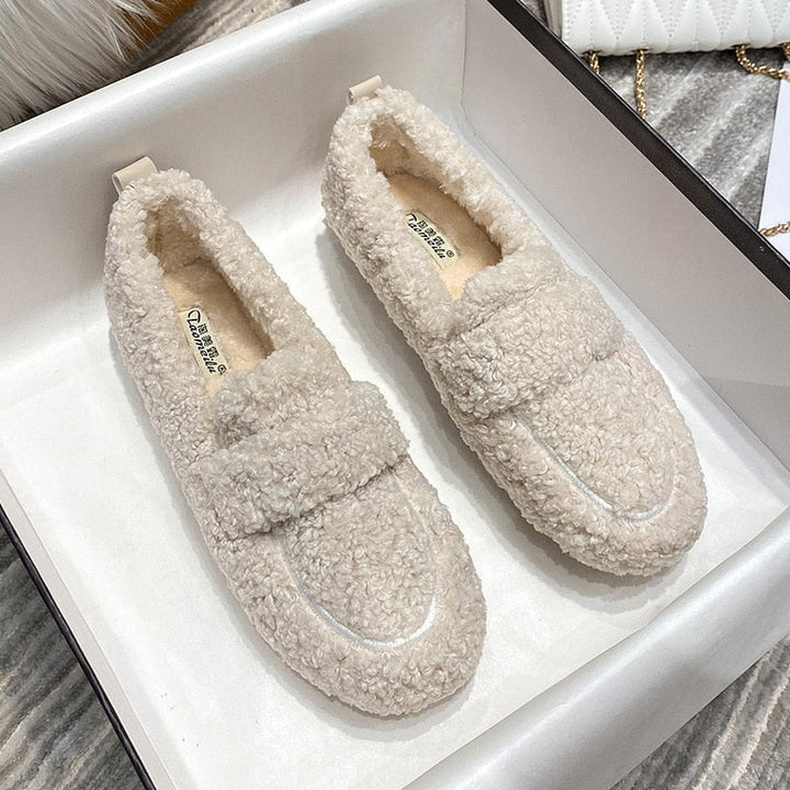 Ein Paar cremefarbene Plüsch-Pantoffel-Schuhe