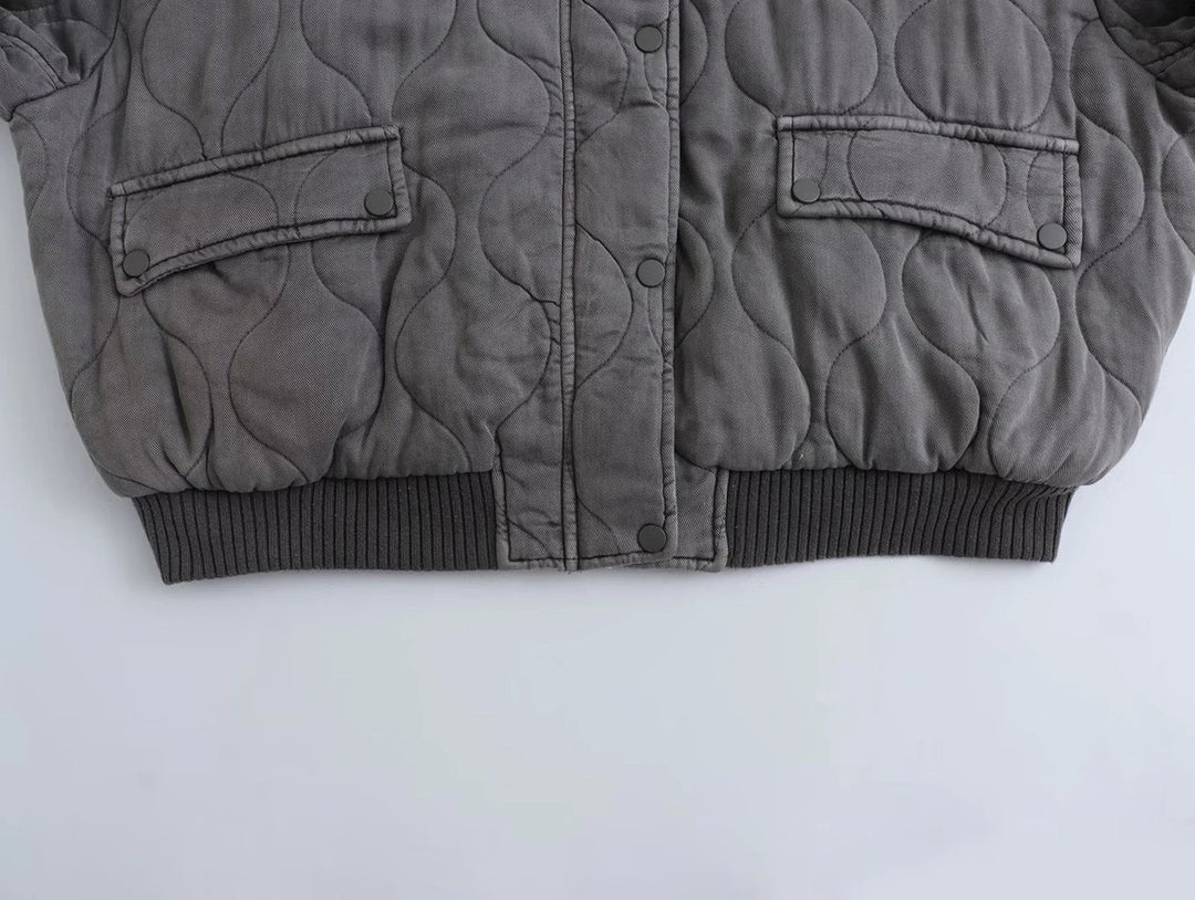 Eine Nahaufnahme des Saums und der Manschetten einer grauen Bomberjacke, die ihr strukturiertes Design zeigt.