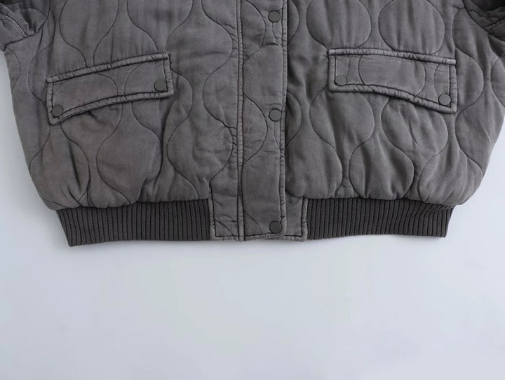 Eine Nahaufnahme des Saums und der Manschetten einer grauen Bomberjacke, die ihr strukturiertes Design zeigt.