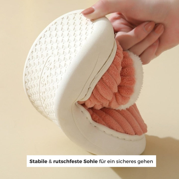 Hand, die die sohle eines warme pinke hausschuhe hält